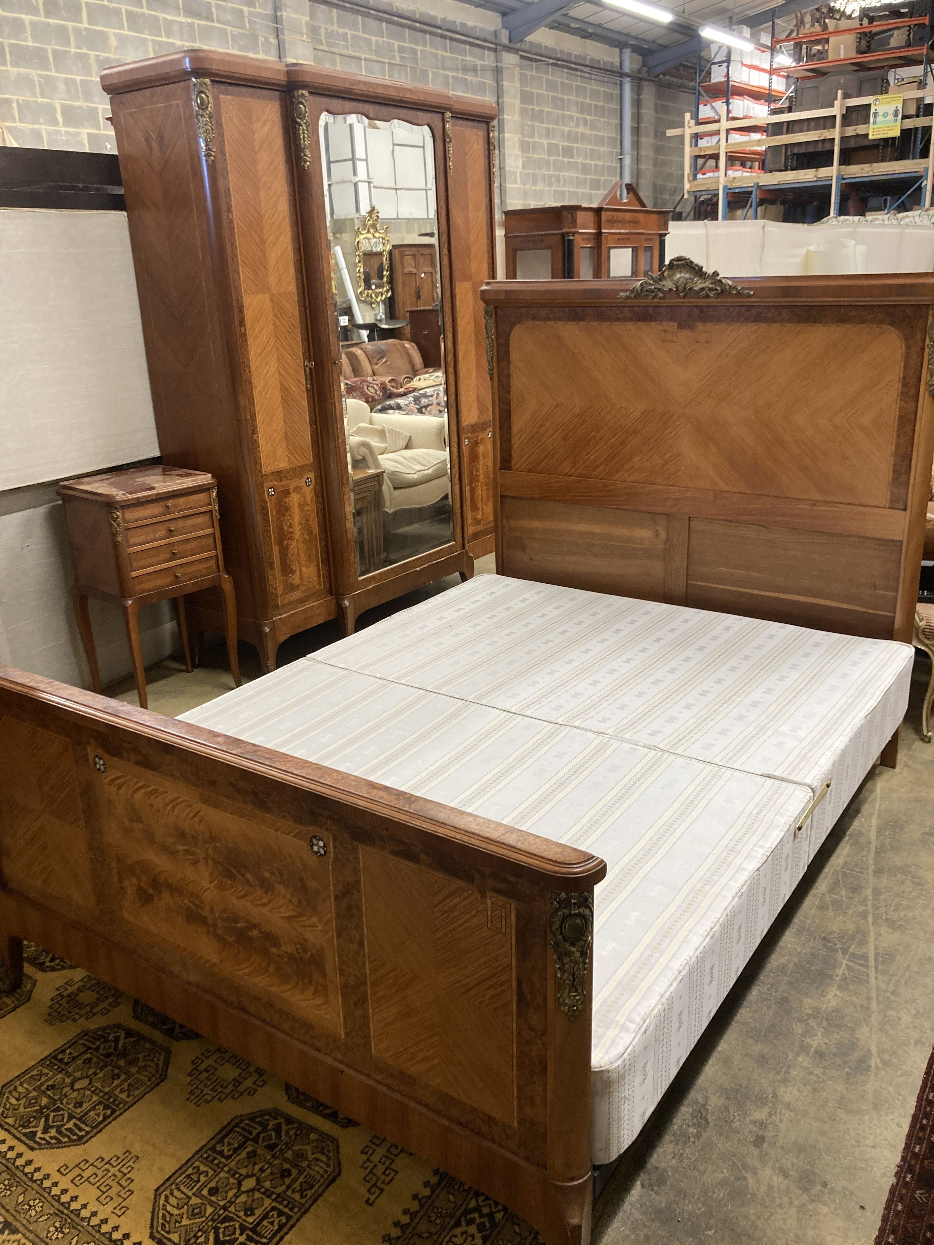 A Louis XVI style three piece gilt metal mounted kingwood bedroom suite, consisting:- an armoire, a bedstead and a marble topped bedside cupboard, armoire W.174cm D.55cm H.224cm